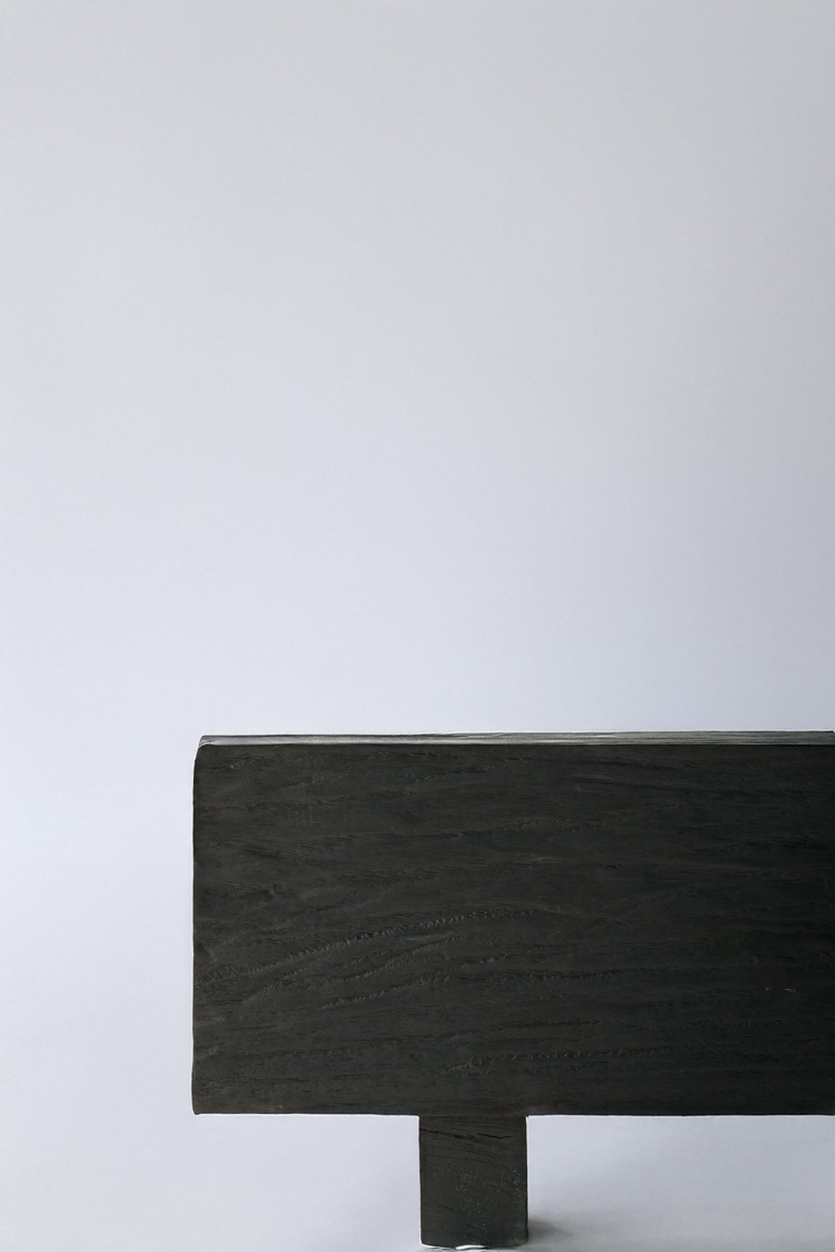 The end of the bench and one foot against a pale ground