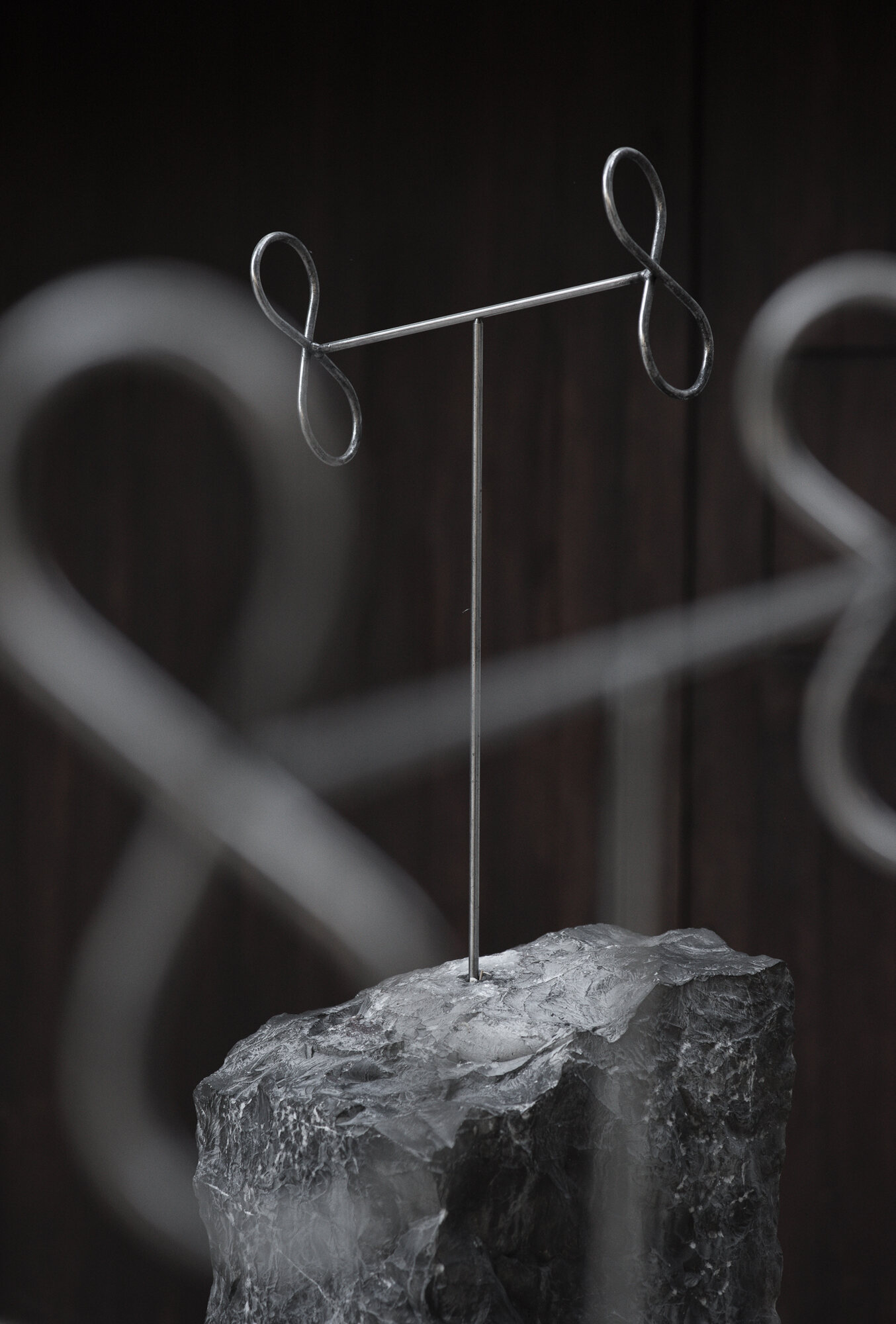 Steel T-form above stone, with a blurred loop in the foreground