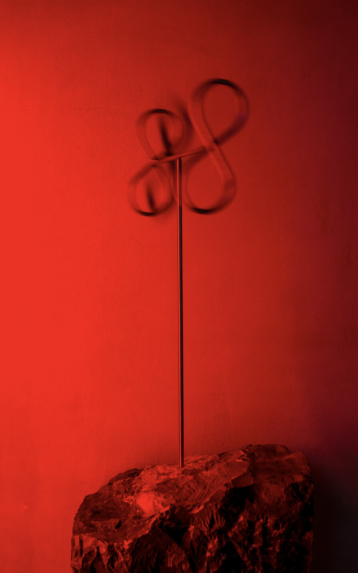 Steel loops blurred mid-spin above a stone, lit red